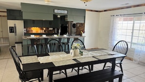 A dining area with a table set for four, a kitchen in the background, and a ceiling fan. - Quiet Country Getaway ,quiet, and spacious getaway (Belen)