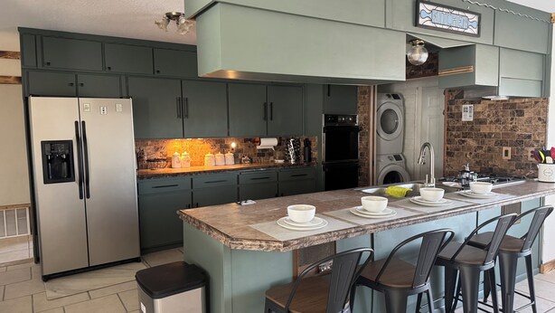 A kitchen with a central island, bar stools, a refrigerator, an oven, and a washing machine. - Quiet Country Getaway ,quiet, and spacious getaway (Belen)