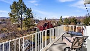 Une terrasse avec des meubles d’extérieur, une grange rouge et un paysage montagneux en arrière-plan.