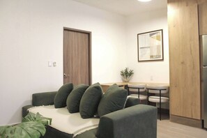 A living room with a sofa, a small table, and chairs. There is a door and a framed picture on the wall. - +MS +Única Suite +Inmejorable ubicación +Internet (Santiago de Querétaro)