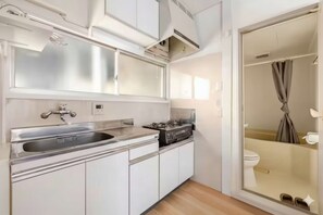 Una cocina compacta con lavamanos, estufa y armarios.