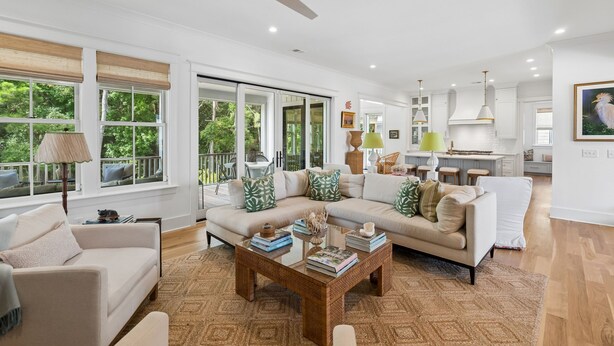 A spacious living area with a sofa, coffee table, and a view of the outdoors. - 8311 Jack Island Dr – 4 BR / Walk to Spring House / Elevator + Screened Porch (Johns Island)