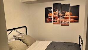 A bedroom with a bed, a ceiling light fixture, and a wall-mounted picture.