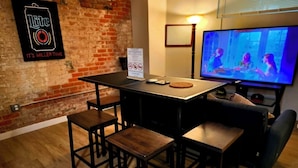 A room with a brick wall, a table with chairs, a television, and a sign on the wall.