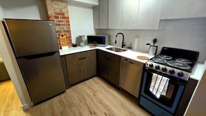 A modern kitchen with a refrigerator, microwave, sink, stove, and dishwasher.
