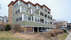 A multi-story building with a garage, a sign for 'Bretzle Glass,' and a parked car. - Lake Michigan Condo | Walk to Downtown | Views + Parking (Grand Haven)