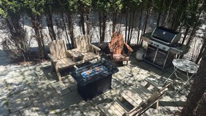 Une terrasse dotée de meubles en bois, d’un foyer extérieur et d’un barbecue.