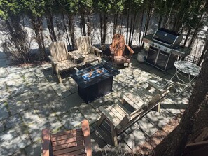 En terrasse med træmøbler, en pejseplads og grill.