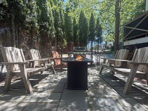 Une terrasse extérieure avec un barbecue, des chaises en bois et une table.