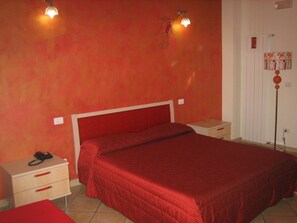 A room with a single bed, a bedside table with a phone, a nightstand, and a wall-mounted lamp. - Residenza Glave (Campomarino)