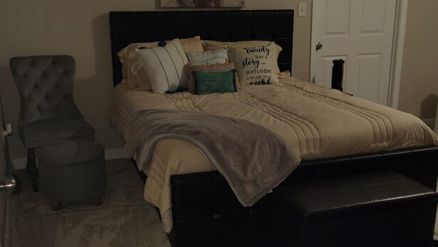 A bedroom with a bed, a chair, a rug, and a door. - Welcome to the Pool House Retreat! (Jonesboro)