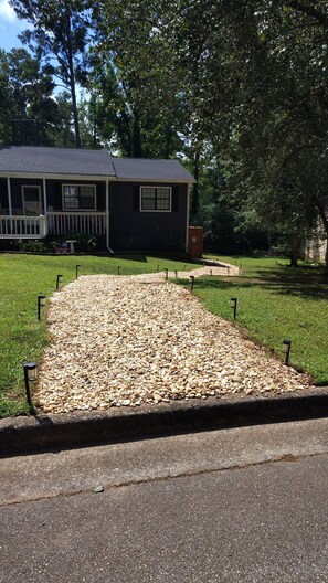 A house with a gravel driveway, a lawn, and a wooden deck. - Welcome to the Pool House Retreat! (Jonesboro)