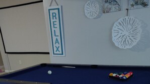 A pool table with a 'RELAX' sign, a cue ball, and a rack of billiard balls. - Welcome to the Pool House Retreat! (Jonesboro)