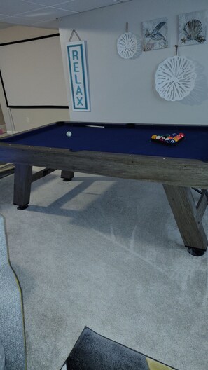 A pool table with a 'RELAX' sign, a cue ball, and a rack of billiard balls. - Welcome to the Pool House Retreat! (Jonesboro)
