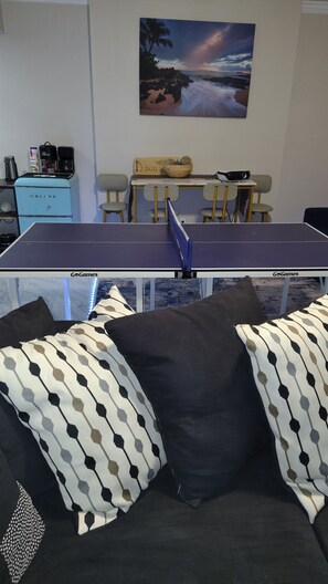 A ping pong table with GoGames branding, a coffee machine, and a painting of a beach scene on the wall. - Welcome to the Pool House Retreat! (Jonesboro)