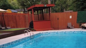 A swimming pool with a wooden deck and a covered area. - Welcome to the Pool House Retreat! (Jonesboro)