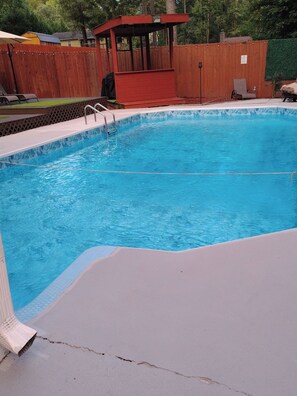 A swimming pool with a wooden deck and a covered area. - Welcome to the Pool House Retreat! (Jonesboro)
