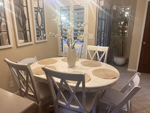 Un coin repas avec une table ronde, des chaises blanches et un vase décoré de branches.