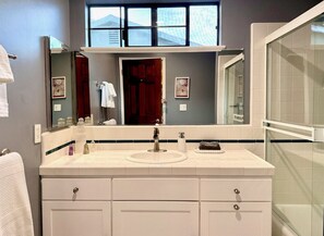 Une salle de bain avec un grand miroir, un lavabo et une douche.