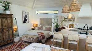 A cozy, well-lit room with a bed, a sofa, a dining area, and a kitchen.