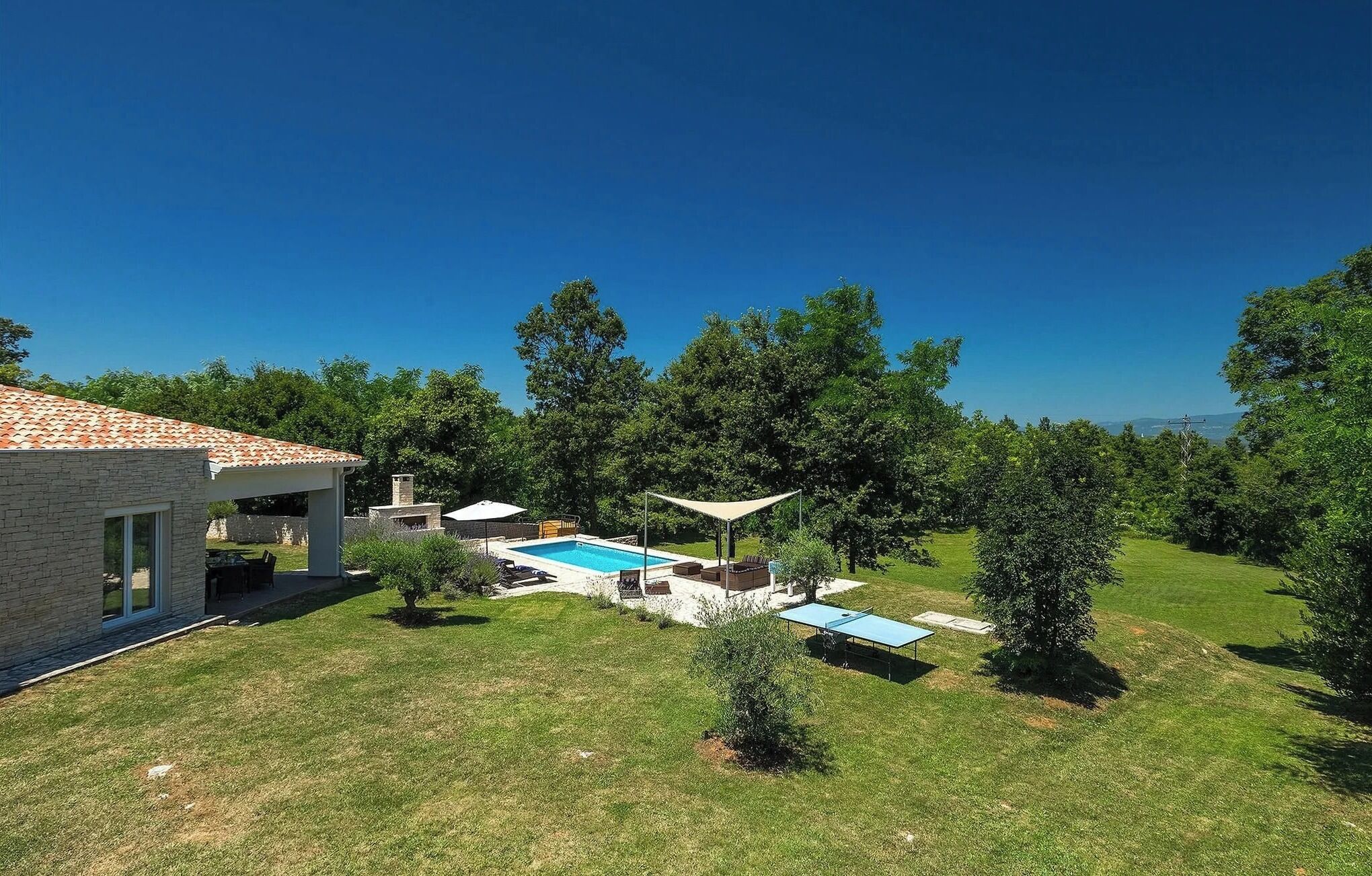 Une propriété résidentielle dotée d’une piscine, d’un espace extérieur aménagé et d’une terrasse couverte.
