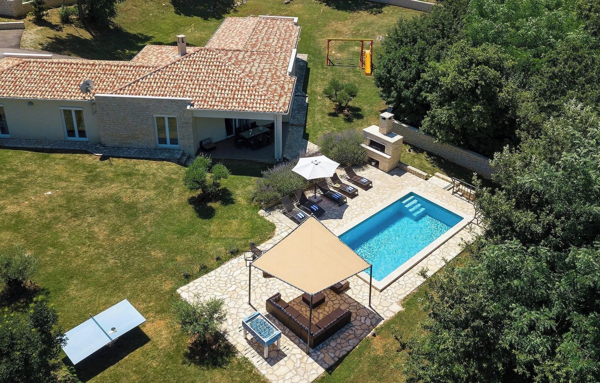 Ein Haus mit Schwimmbad, Sitzgelegenheiten im Freien und einer Terrassenfläche.