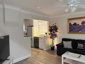 A modern living room with a flat-screen TV, a black sofa with patterned cushions, a white coffee table, and a potted plant with colorful lights. - Lovely House walking to Niagara Falls in Canada (Niagara Falls)