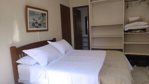 A bedroom with a bed, a wardrobe, and a painting on the wall. - Cozy house with pool, air conditioning, barbecue, and garage. (Armação dos Búzios)