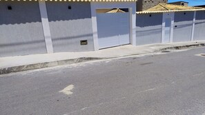A street with a row of white buildings, a sidewalk, and a road. - Cozy house with pool, air conditioning, barbecue, and garage. (Armação dos Búzios)