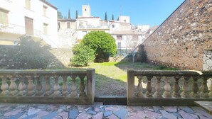 A courtyard with stone walls, a small tree, and a view of buildings in the background. - Beautiful home in Cessenon sur Orb with WiFi (Cessenon sur Orb)