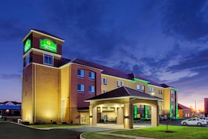 A multi-story hotel with a prominent sign, a covered entrance, and a parking lot. - La Quinta Inn & Suites Indianapolis Airport West (Plainfield)