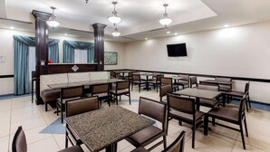 A hotel dining area with multiple tables and booths, ceiling fans, and a flat-screen TV on the wall. - La Quinta Inn & Suites Indianapolis Airport West (Plainfield)