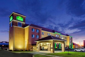 A multi-story hotel with a prominent sign, a covered entrance, and a parking lot. - La Quinta Inn & Suites Indianapolis Airport West (Plainfield)