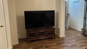 Una habitación con un mueble de entretenimiento de madera, un televisor de pantalla plana y una puerta que da a otra estancia.