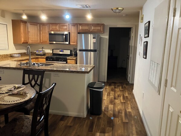 Una cocina con armarios de madera, un refrigerador de acero inoxidable, un microondas y una estufa.