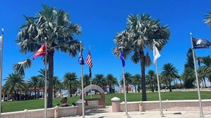 A plaza with palm trees, flags, and a sign. - Clearwater Paradise/Hot Tub & Backyard Bliss/Near Beach+Hotspots (Clearwater)