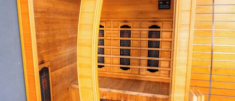 A wooden sauna with a sloped ceiling, a ventilation system, and a control panel.