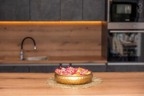 A kitchen with a wooden countertop, a gold-rimmed bowl with colorful items, a sink, and a modern oven.