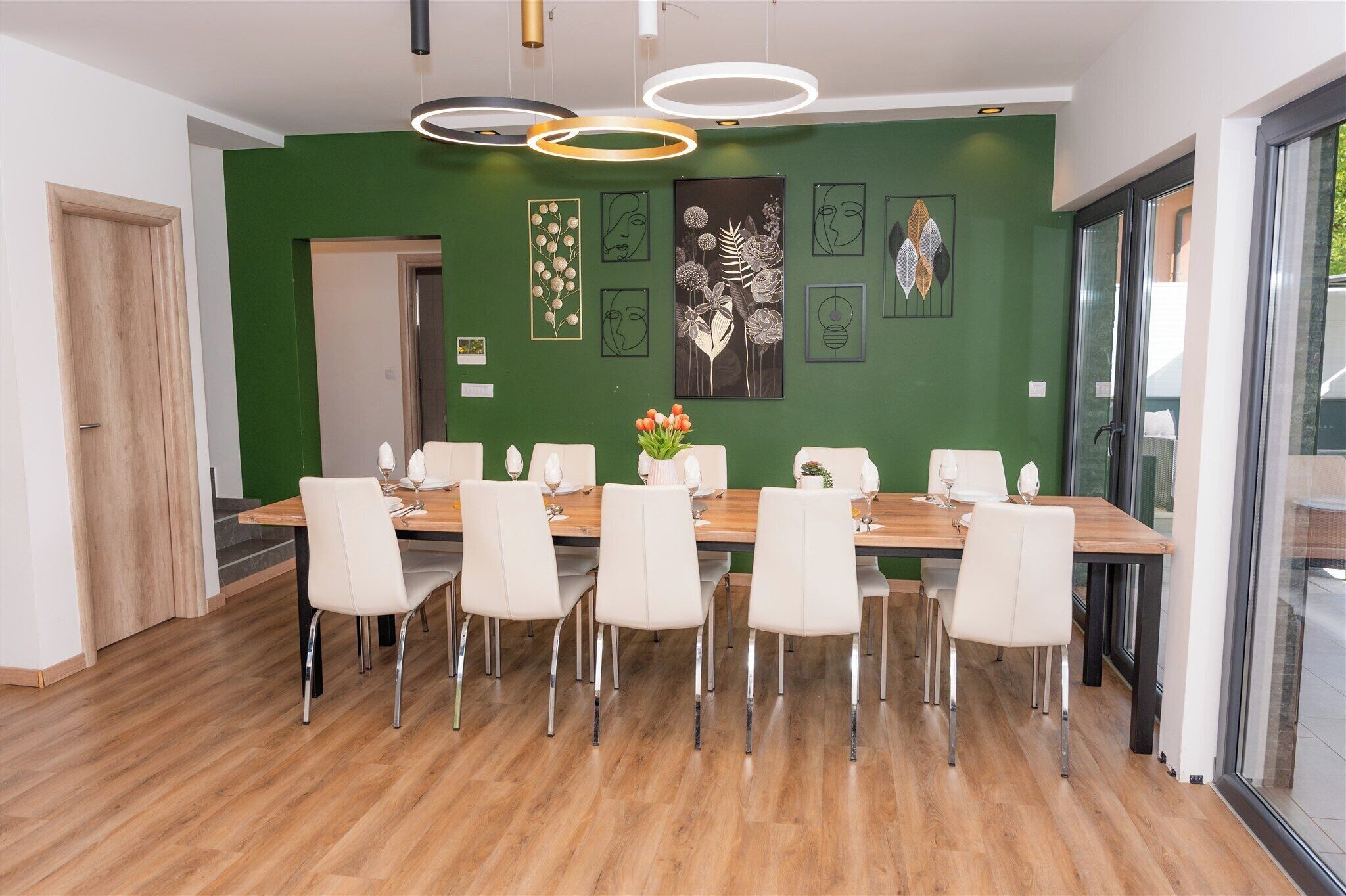 A dining area with a wooden table, white chairs, and a green accent wall.