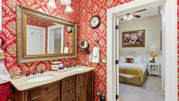 A bathroom with a double sink vanity, a large mirror, and a red patterned wall.