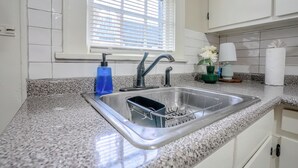 A kitchen with a granite countertop, stainless steel sink, and white cabinets. - Centrally Located King Bed Midtown Crosstown 1428 (Memphis)