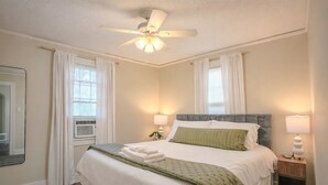 A neatly made bed with a green throw, a ceiling fan, and two bedside lamps in a well-lit bedroom. - Centrally Located King Bed Midtown Crosstown 1428 (Memphis)