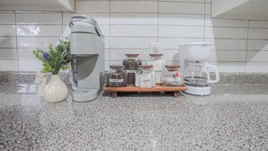 A kitchen counter with a coffee maker, a coffee pot, and jars labeled with contents like decaf, coffee, sugar, cream, and tea. - Centrally Located King Bed Midtown Crosstown 1428 (Memphis)