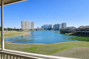 A view of a lake with surrounding buildings, a golf course, and a clear blue sky. - Private Beach☀️Lakeview Home | Tennis | Pickleball | Playset | 5 Pools, 3 Heated ☀️Seascape (Miramar Beach)