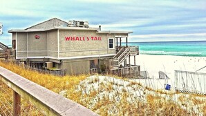 En redningsplatform med skiltet "Whale's Tail" på en strand med en træbro, der fører hen til den.