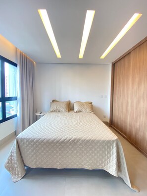 A modern hotel room with a large bed, bedside tables, a view through the window, and a wooden panel wall.