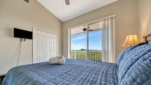 A bedroom with a bed, a TV, a ceiling fan, a window with a view, and a lamp. - Waterview Townhome Sleeps 4! Heated Pool & Hot Tub (Ruskin)