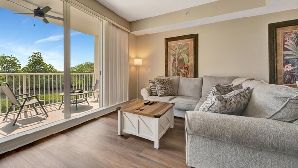 A spacious living room with a balcony, a ceiling fan, a sofa, a coffee table, and a painting on the wall. - Waterview Townhome Sleeps 4! Heated Pool & Hot Tub (Ruskin)