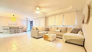 A spacious living area with a sofa set, a coffee table, and a dining table with chairs.