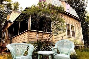 A wooden house with a porch and two wicker chairs. - Acadian Dreams- Entire home next to Acadia (Mount Desert)